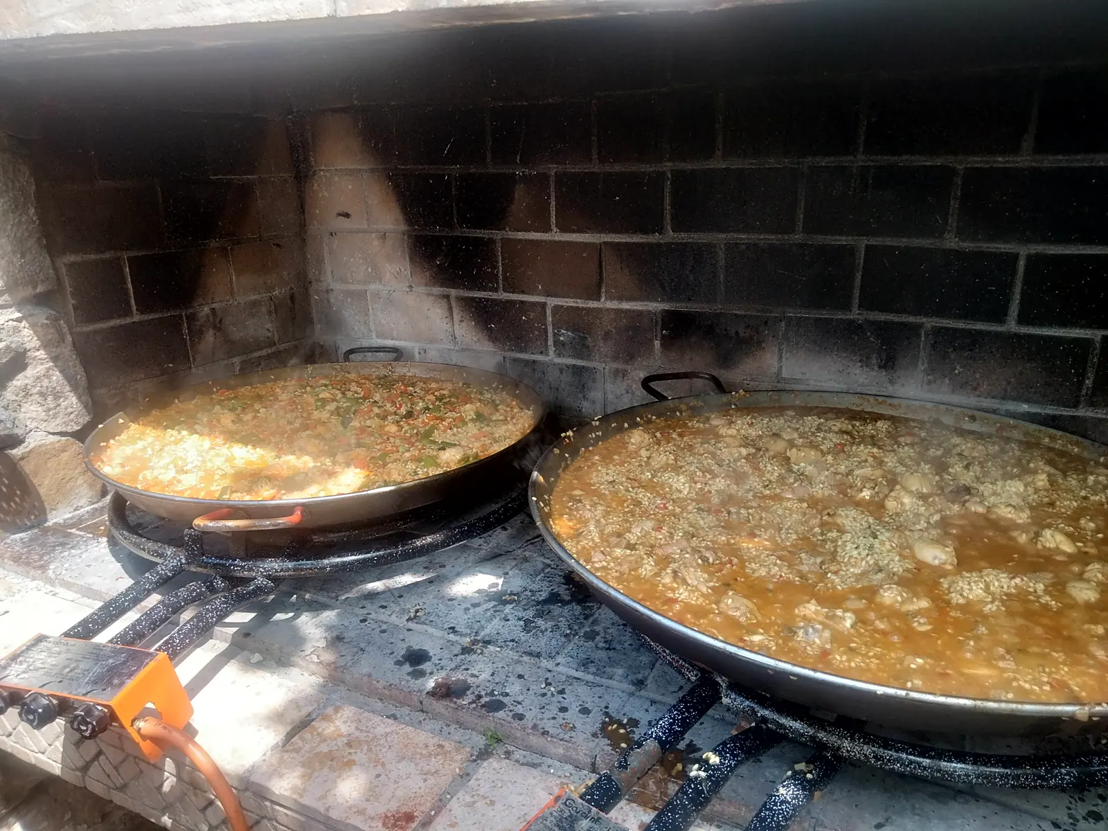 Dos paellas al fuego de leña en una parrilla de obra
