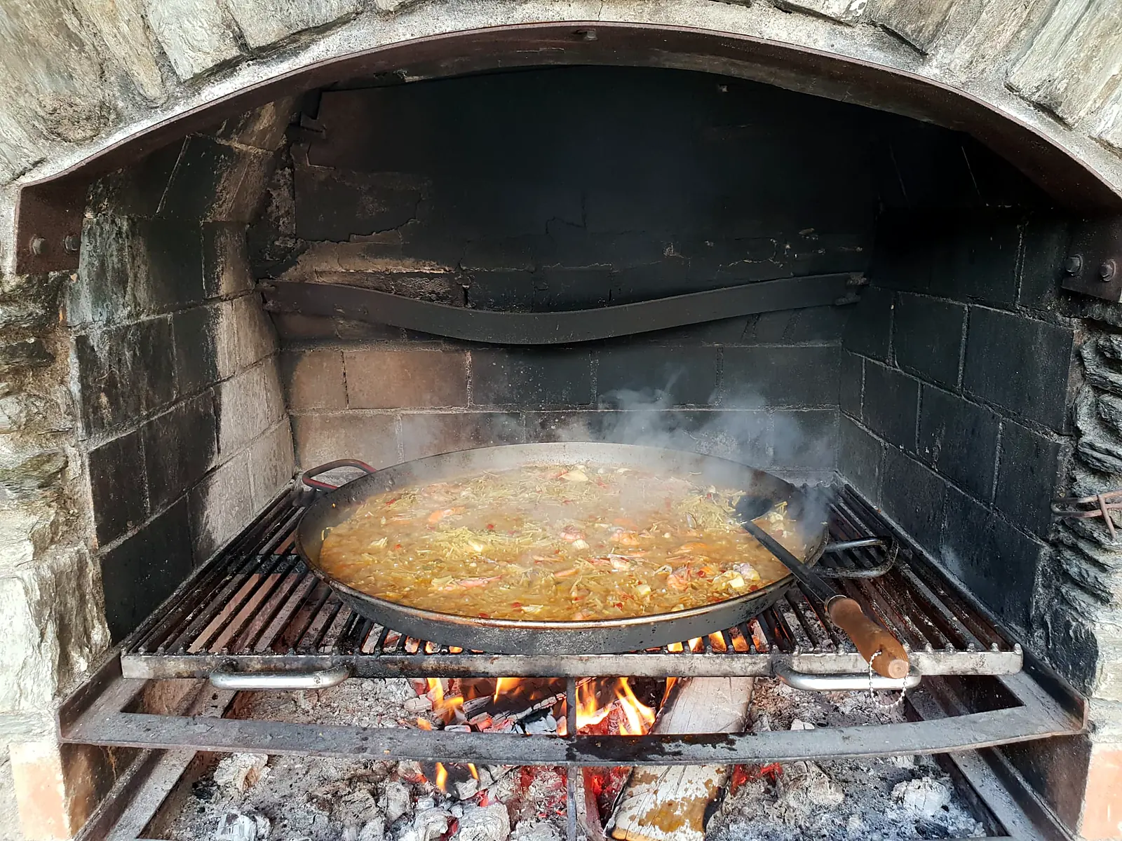 Paella cociéndose a la leña en una chimenea