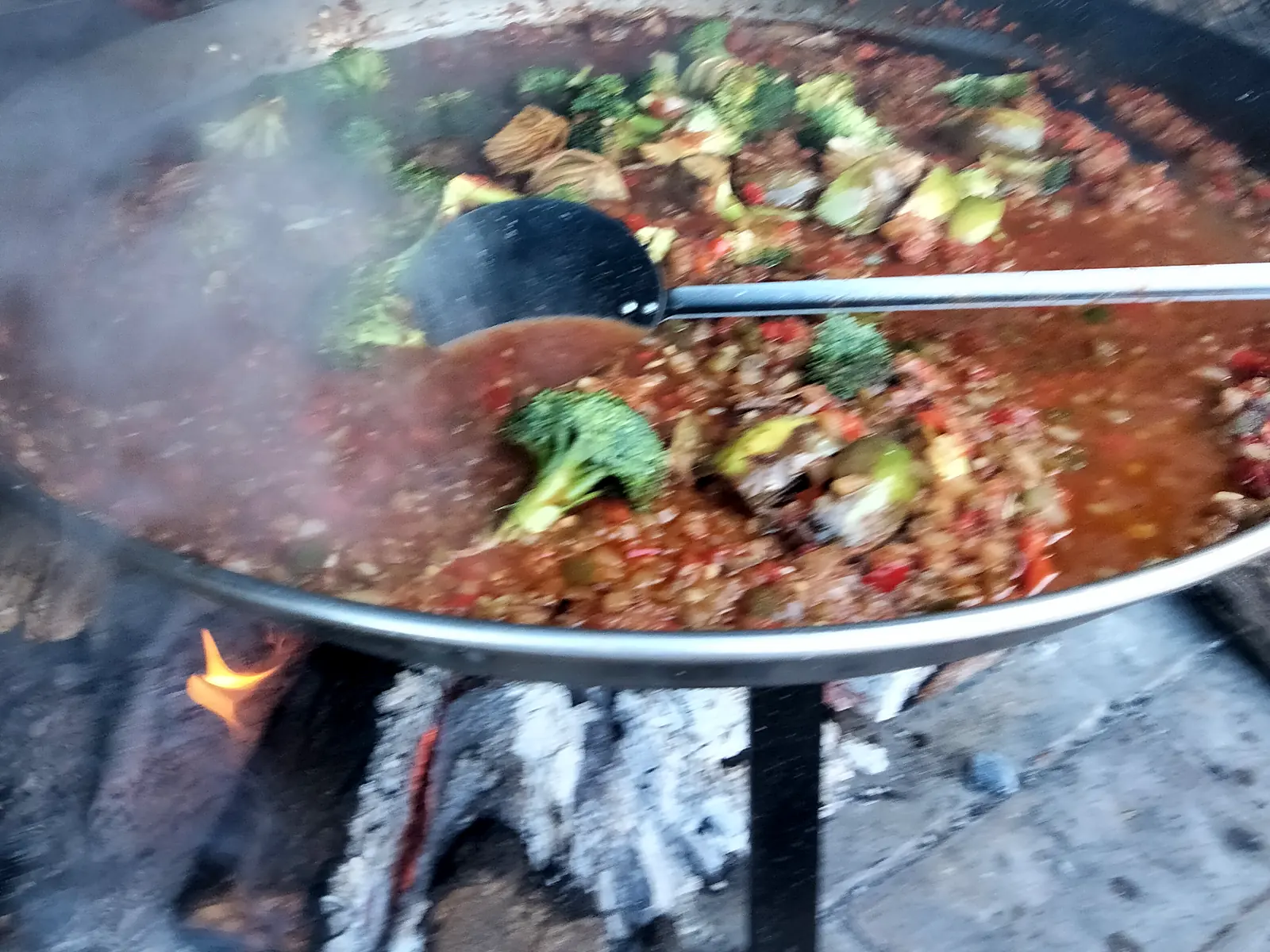 Paella de verduras cociéndose a la leña